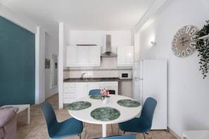 A modern kitchen with white cabinets, a stainless steel range hood, and a white refrigerator.