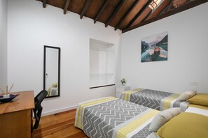 A room with two beds, a desk, a mirror, and a painting on the wall. - Vacation Home 'Casa Rural Tacoronte' with Private Terrace and Wi-Fi (Tacoronte)