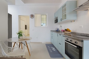 A modern kitchen with light blue cabinets, a stainless steel oven, and a dining area with a table and chairs.