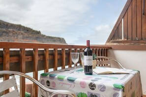 Een balkon met een tafel gedekt voor twee, een fles wijn en een boek.