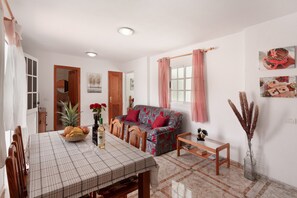 A dining area with a table set for two, a sofa, and a small side table.