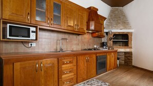 A kitchen with wooden cabinets, a microwave, a sink, a stove, and a brick oven. - Vacation Apartment 'Teide' with Wi-Fi (Icod de los Vinos)