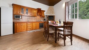 A kitchen with wooden cabinets, a microwave, a stove, and a dining table with chairs. - Vacation Apartment 'Teide' with Wi-Fi (Icod de los Vinos)