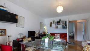 A modern living room with a glass dining table, red sofa, and a bookshelf. - La Ville Allis by Interhome (Saint Malo)