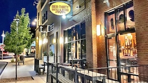 A building with a sign for 'Bier-THIRTY Bottle & Bistro' and a sidewalk with a tree and benches. - Westerhaven | Western-Themed Garden Suite • Pet Friendly • 2 Queen Beds • Near I-84 • Nampa (Nampa)