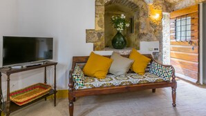 A cozy living room with a wooden sofa, a TV on a stand, and a stone archway. - La Torre by Interhome (Sovicille)