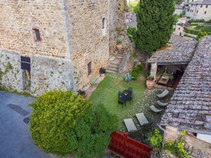 A stone building with a courtyard, outdoor seating, and potted plants. - La Torre by Interhome (Sovicille)