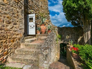 A stone staircase leading to a white door, surrounded by potted plants and greenery. - La Torre by Interhome (Sovicille)
