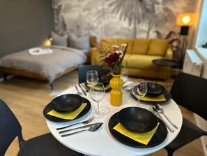 A dining table set with black plates, yellow napkins, and silverware, with a vase of flowers in the center.
