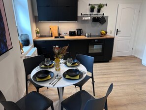 A modern kitchen with black cabinets, a wooden countertop, and a dining area with a white table set for four.
