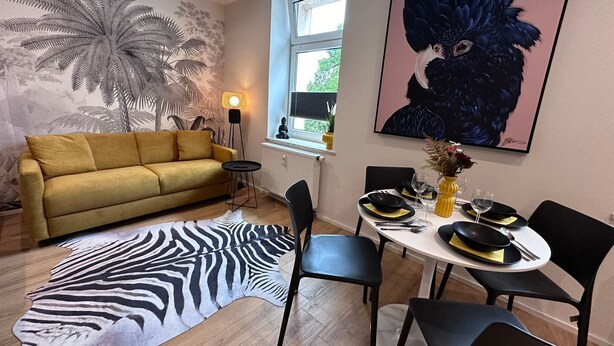 Uma sala de estar moderna com um sofá, mesa de jantar, cadeiras e um tapete de zebra.