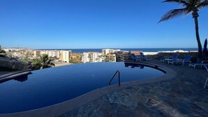 A pool with a view of the ocean and cityscape.