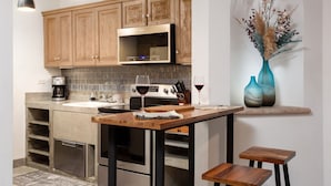 A modern kitchen with wooden cabinets, a stainless steel microwave, and a dining area with a wooden table and stools.