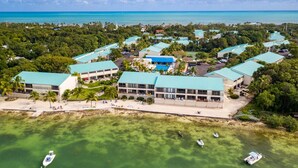 Oversigtsbillede af et resort med flere bygninger, en strand og klart turkis vand.