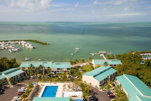 A resort with a swimming pool, multiple buildings, and a marina with boats.