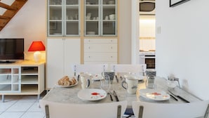 A compact kitchen with a dining table set for two, a television, and a red lamp. - La Pommeraie by Interhome (Villers sur mer)