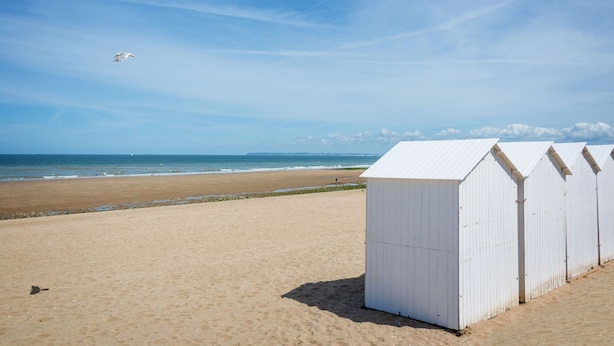 A beach with white beach huts and a clear sky. - La Pommeraie by Interhome (Villers sur mer)