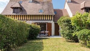 A two-story house with a sloped roof, a front porch, and a small garden area. - La Pommeraie by Interhome (Villers sur mer)