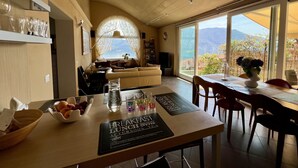 A dining area with a table set for breakfast, lunch, and afternoon tea, with a view of the sea and mountains.
