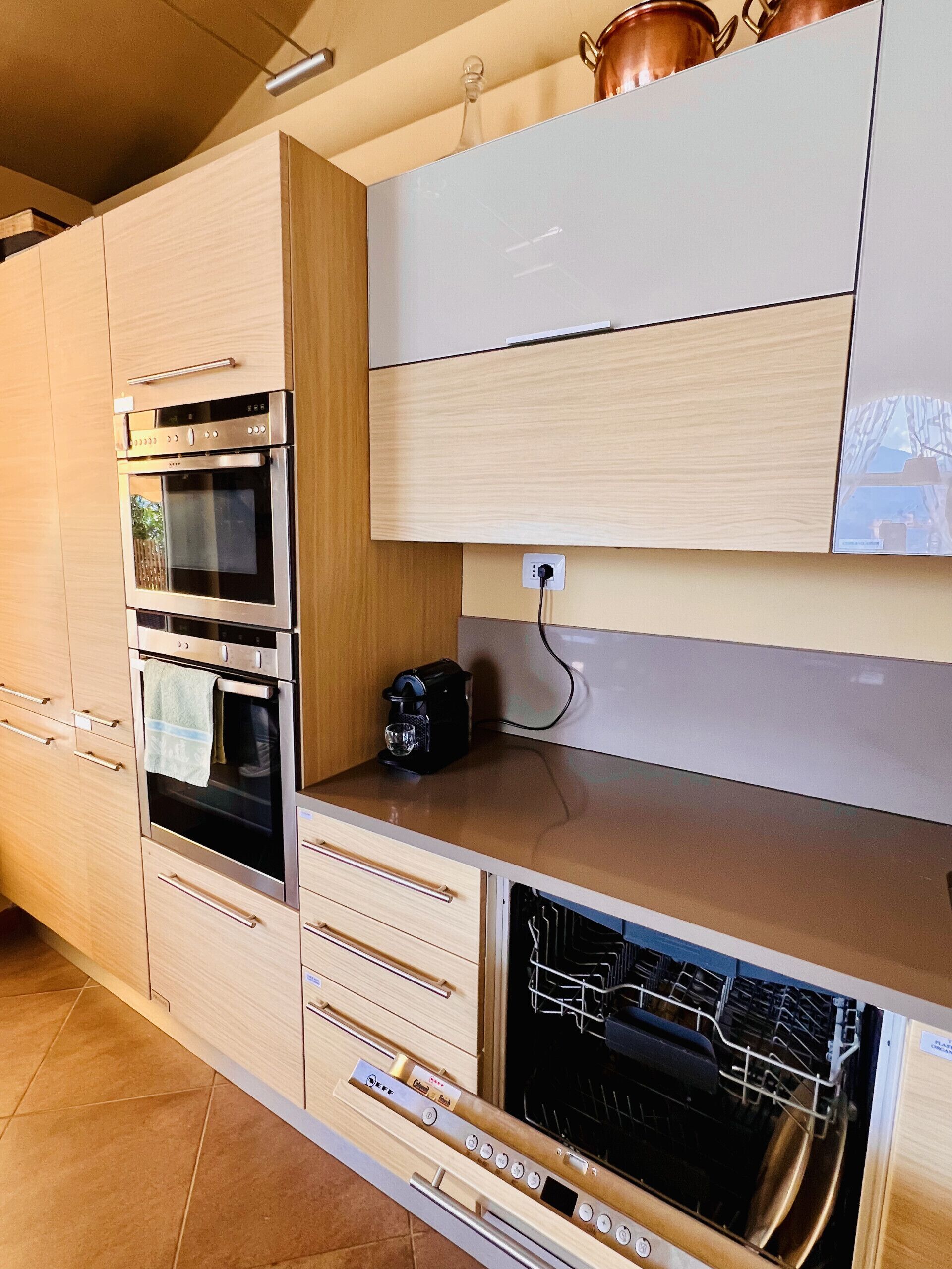 A modern kitchen with built-in ovens, a coffee machine, and a dishwasher.