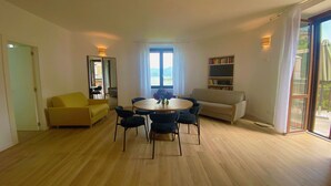 A spacious living area with a round table and chairs, a sofa, and a bookshelf. - Eva Apartament with Lake View in Baveno (Baveno)