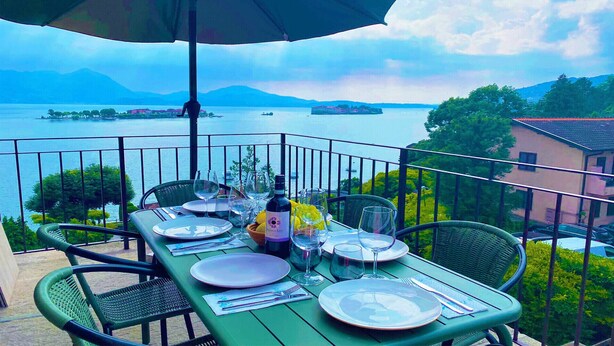 A table set for dining with a view of a lake and mountains. - Eva Apartament with Lake View in Baveno (Baveno)