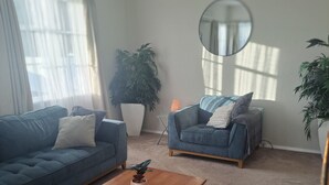 A living room with two sofas, a coffee table, and potted plants.