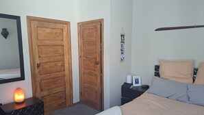 A bedroom with a bed, a nightstand, a heater, and two wooden doors.