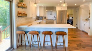 A modern kitchen with a large island, bar stools, and a view of the outdoors. - Valley View Villa - Modern Farmhouse W/ Hot Tub (Dover)