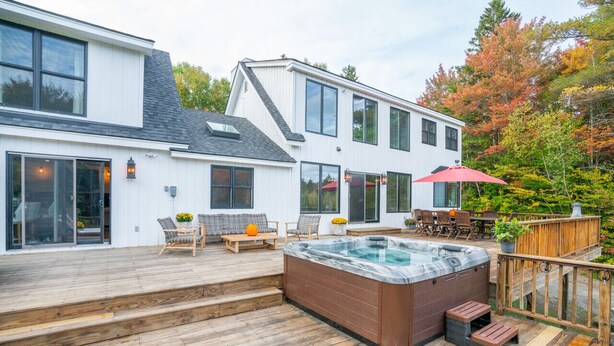 A modern house with a wooden deck, a hot tub, and outdoor furniture. - Valley View Villa - Modern Farmhouse W/ Hot Tub (Dover)