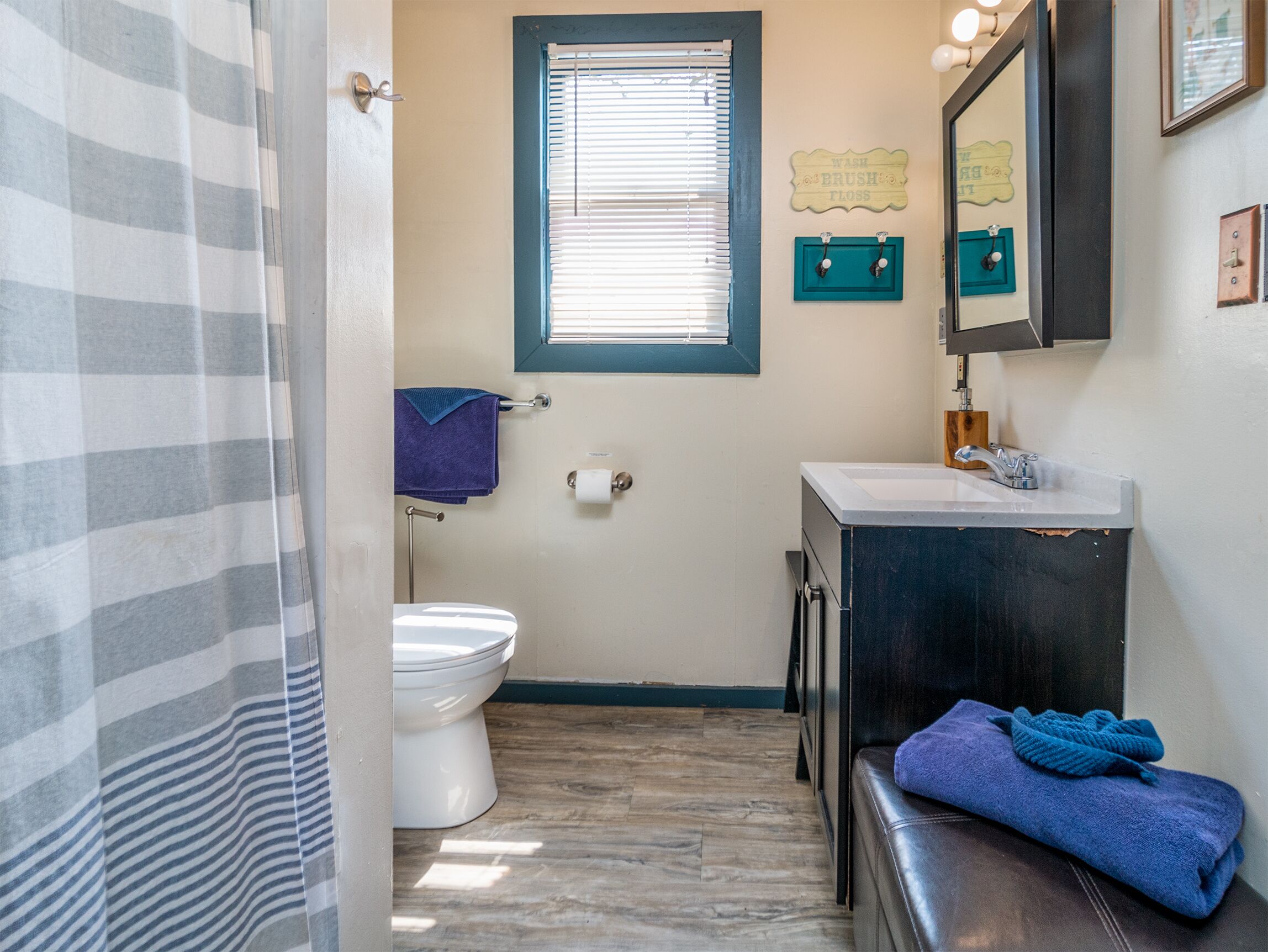 A bathroom with a toilet, sink, and window.