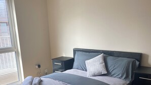 A bedroom with a bed, nightstands, and a window with blinds.