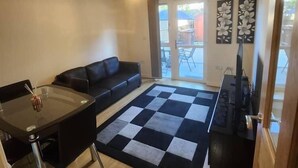 A compact living space with a dining area, sofa, and a checkered rug.