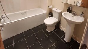 A bathroom with a bathtub, toilet, and sink.