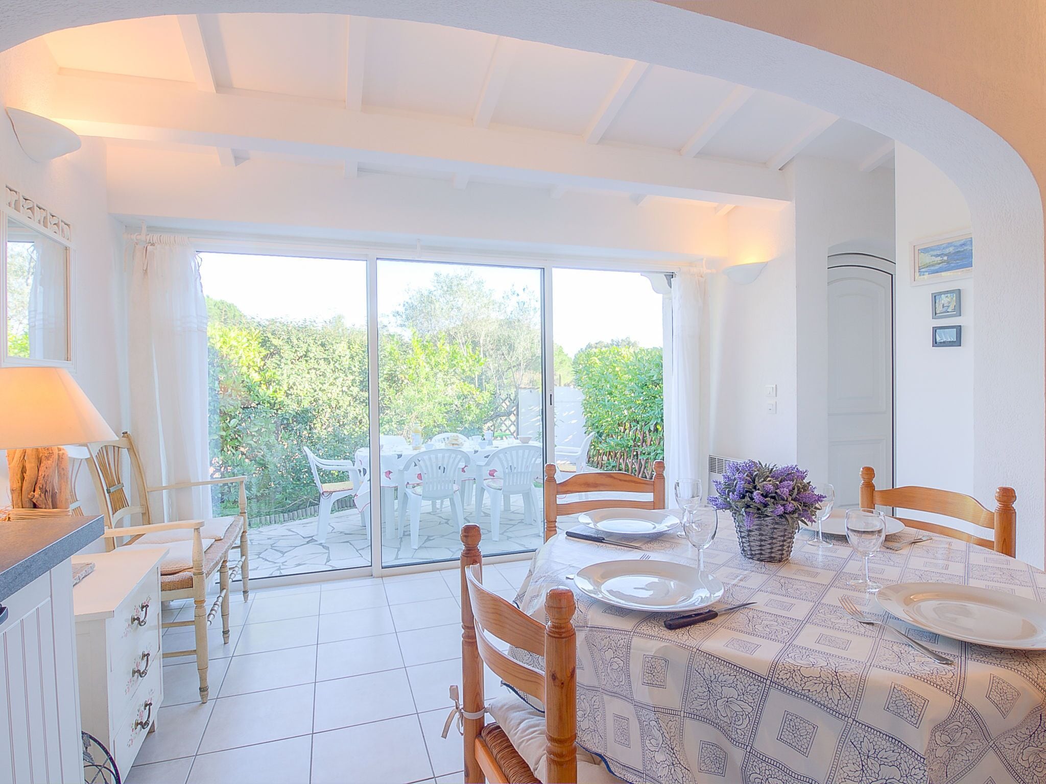 A dining area with a table set for four, a bench, and chairs.