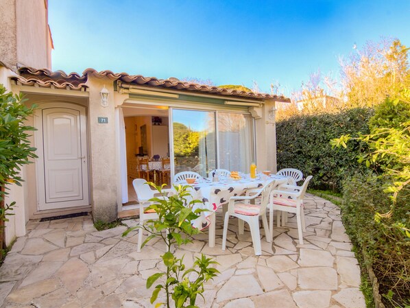 A patio with a stone floor, white chairs, and a table set for dining.