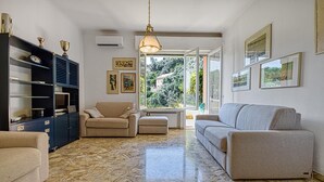 A living room with a marble floor, a sofa, a chair, and a bookshelf. - Amazing apartment in Camogli with WiFi (Camogli)