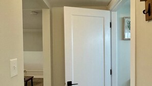 A hallway with a white door, a small bench, and a light switch on the wall. - Chic, Cozy & New! Great location, Street Parking with AC (Renton)