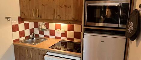 Een koelkast, een vaatwasser, kookgerei, borden en bestek