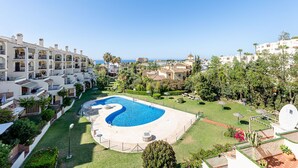 Un complexe hôtelier doté d’une piscine centrale, de nombreux balcons et offrant une vue sur la mer.