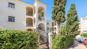 Un immeuble à plusieurs étages doté de balcons, d’une entrée sécurisée et d’un chemin pavé.