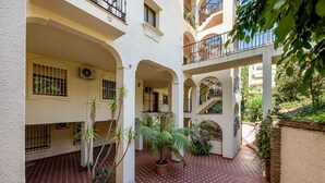 Une cour intérieure à plusieurs niveaux, dotée de sols carrelés, de plantes en pot et de balcons.