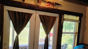 Een kamer met een schuifdeur naar een terras, een plafondventilator en een bank met een decoratief kussen.