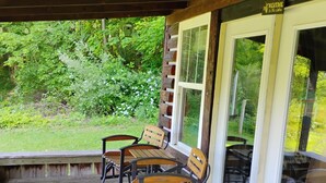Een overdekte veranda met houten banken en een deurmat.
