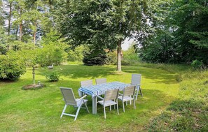 A rectangular outdoor table with a striped tablecloth, surrounded by six chairs with metal frames and fabric seats.