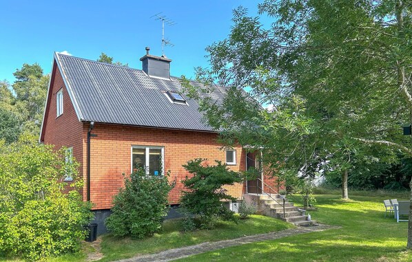 A two-story house with a sloped roof, a chimney, and a small front porch with steps leading to the entrance.