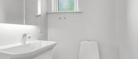 A modern bathroom with a white sink, mirror, and toilet.