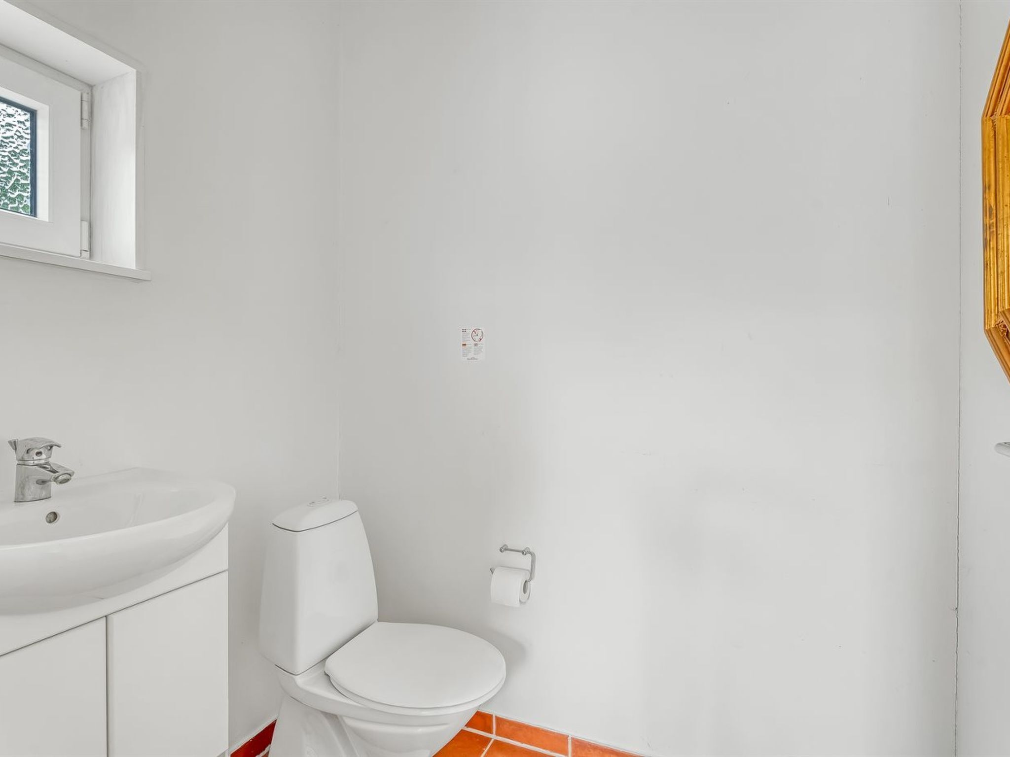 A bathroom with a white sink, toilet, and a window above the sink.