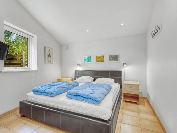 A bedroom with a bed, bedside tables, a window, and artwork on the wall.