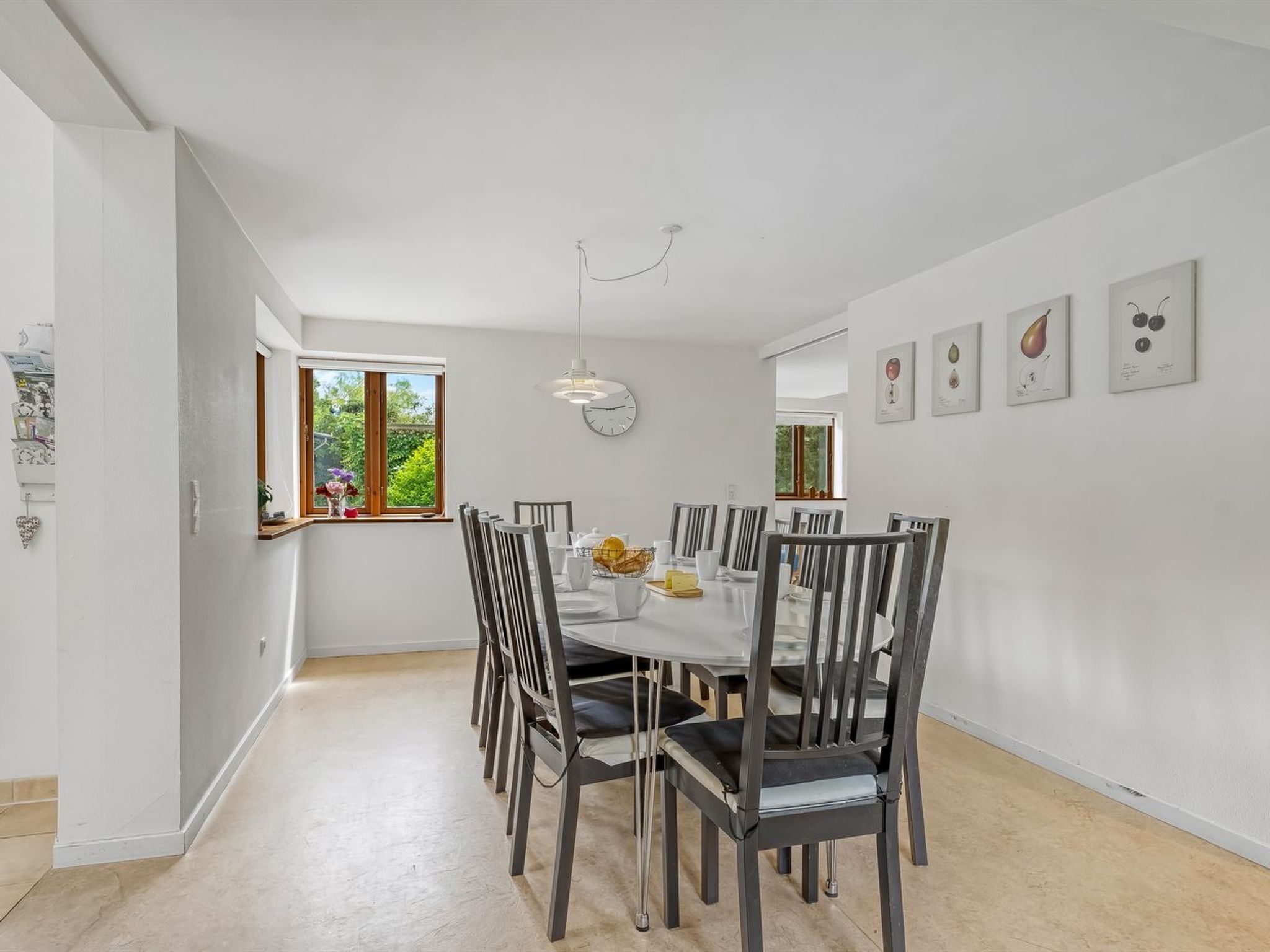 Un espace repas avec une table blanche, des chaises grises et un luminaire suspendu.